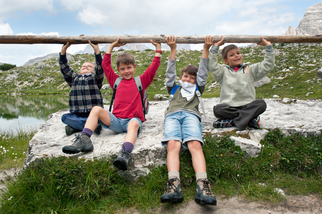 Hiking Tips - Kids playing in the mountains lifting club. Dolomites, Italy.