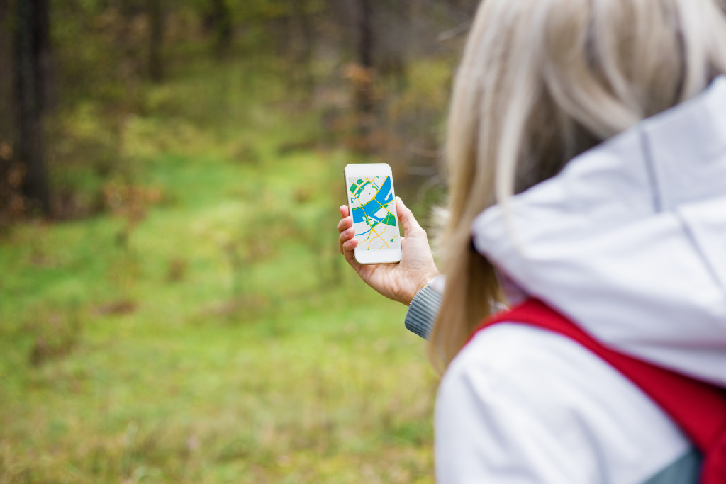 Hiking Tips - Woman geocaching in forest and using mobile app